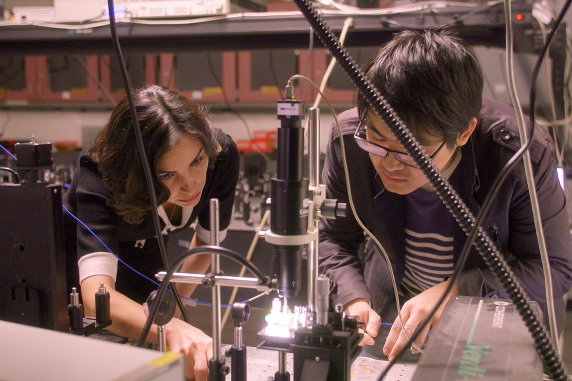 Professor Mona Jarrahi (left) working with her doctoral student Yifan Zhao (right) lean over an optical experiment on a laboratory bench.