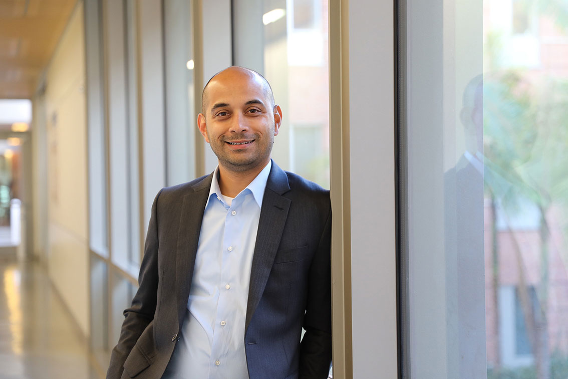 Image of Gaurav Sant in business attire standing inside a building by the window 
